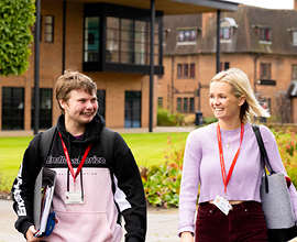 Two students walking along the pathway talking.